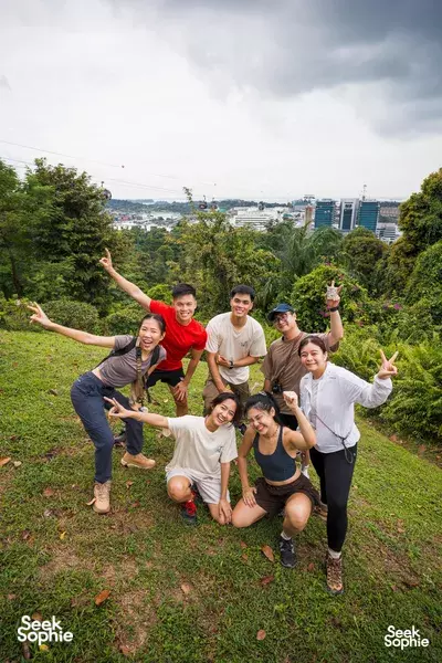 Group of teammates striking playful poses in a grassy park overlooking Singapore’s skyline during team bonding activities Singapore