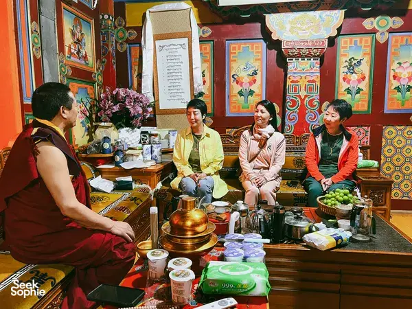 People seated for tea in a colourful Tibetan room in Shangri-La, with a host preparing drinks as part of a home visit