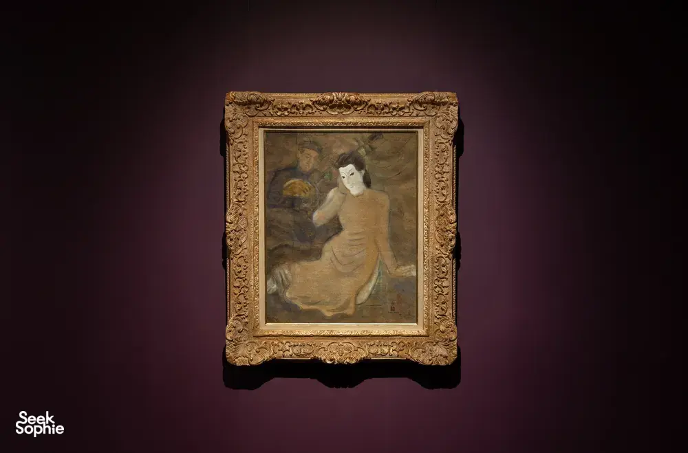Gold-framed portrait painting hanging on a purple wall in Quang San Art Museum, Ho Chi Minh City exhibition hall