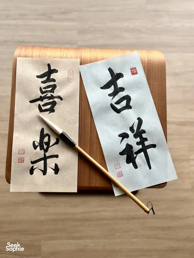 Two Chinese calligraphy sheets on a wooden board with a brush, ready to write a blessing at calligraphy workshops in Singapore