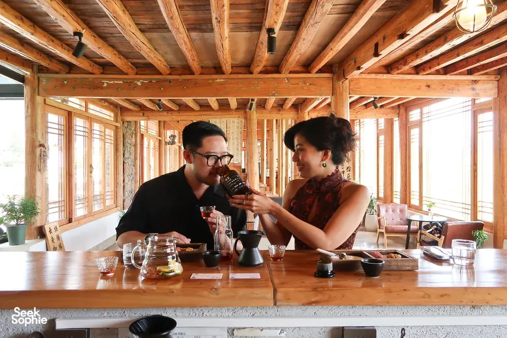 Lijiang coffee workshop tasting inside a timber room, two people pouring and sampling Yunnan coffee at the counter