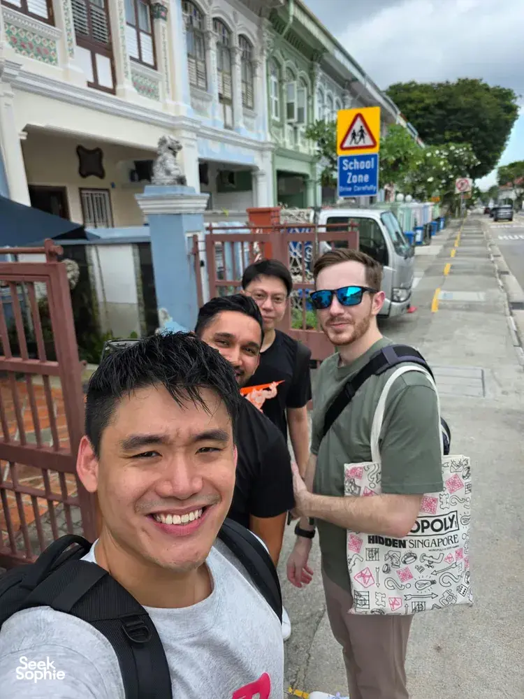 Group on a historic street in Singapore for a real-life Monopoly team game, smiling along the walkway  Singapore hidden gems