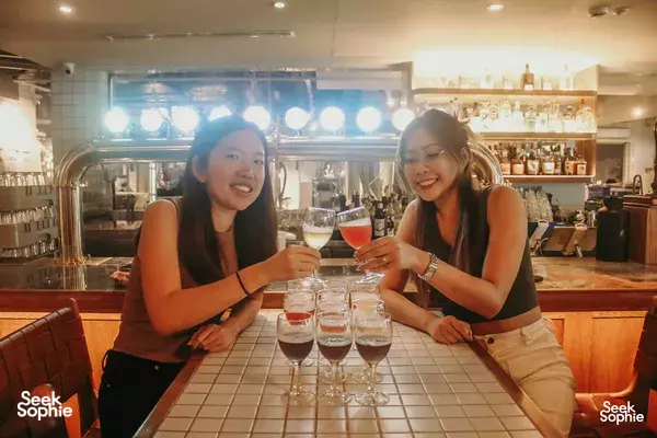 Two friends laughing as they clink craft beer glasses at Lion Brewery Co brewpub in Singapore, one of Singapore hidden gems