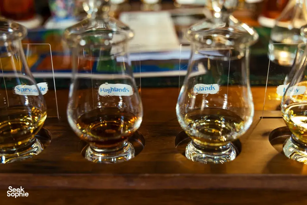 Row of whisky tasting glasses labelled Speyside, Highlands and Islands on a wooden table during Scotch & Sambal’s Singapore session