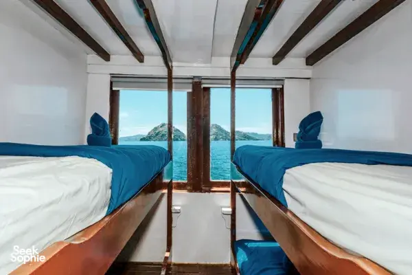 Phinisi interior with two twin berths facing the open stern windows, welcoming ocean views on a private 3D2N Komodo cruise, Komodo Island