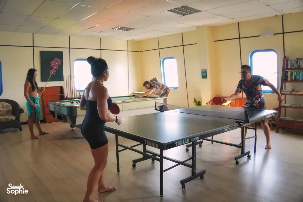 Table tennis in the Seaventures Dive Rig common lounge during a 4D3N offshore rig stay, beside large porthole windows