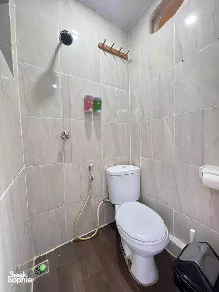 Compact onboard bathroom with white toilet, shower hose and tiled walls on a La Famille 3D2N boat trip to Komodo Island