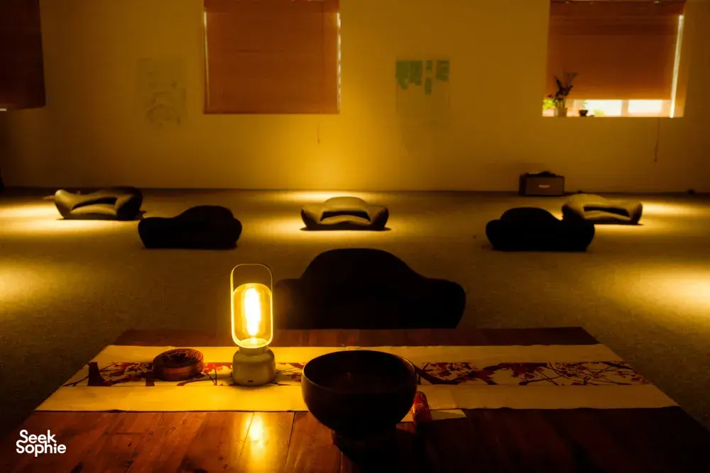 Warm candlelit relaxation room with low cushions and rolled bedding for an agarwood scent experience in Hanoi
