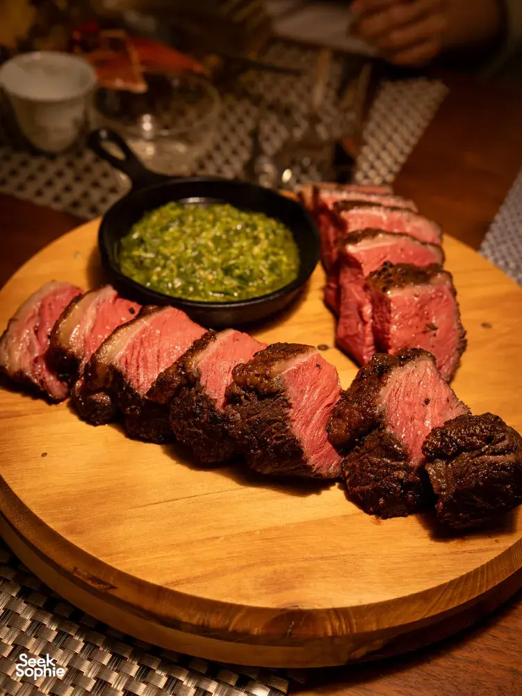 Sliced grilled beef with herb chimichurri on a wooden board at Primateve, private dining Singapore dinner
