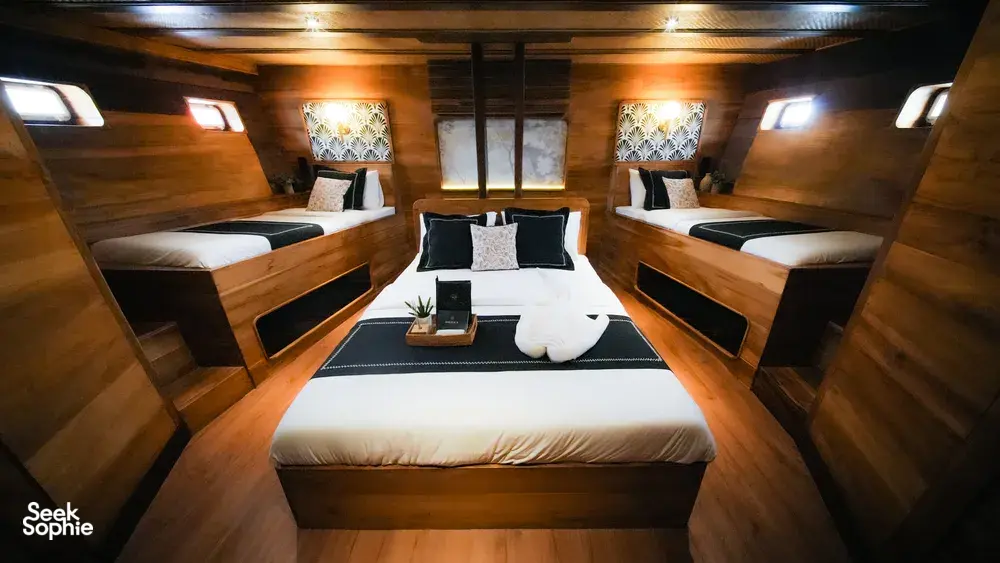 Twin cabin interior on Angelica Liveaboard with neatly made beds and a central table, onboard a 3D2N luxe Komodo cruise in Labuan Bajo