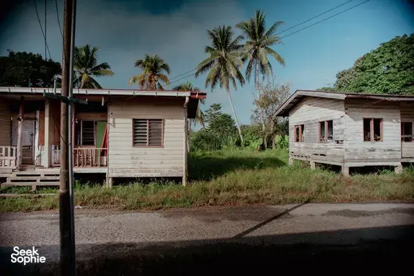 Stilt houses in a quiet tropical village with palm trees and cloudy sky, seen during the Xtreme Paddlers Sabah journey