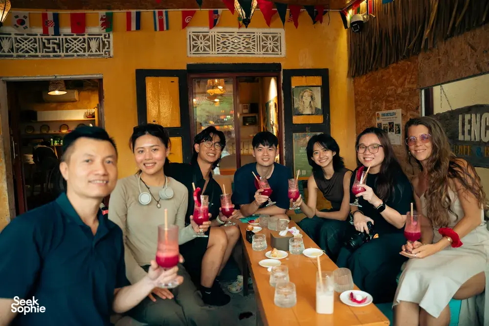 Rakan-rakan di Hoi An bersulang dengan koktel merah berstraw di sebuah tempat tepi jalan yang berwarna-warni semasa menyertai lawatan koktel tersembunyi