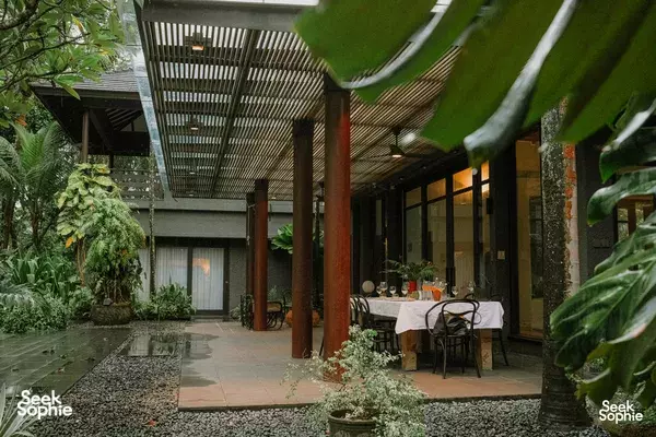 Covered villa courtyard patio with a set dining table and chairs, surrounded by tropical plants and rainforest views in Singapore