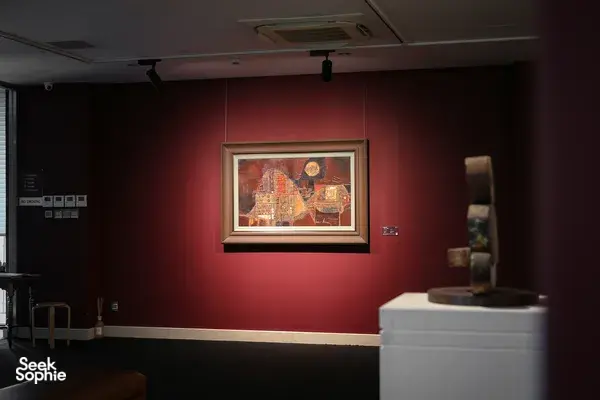 Sebuah lukisan berbingkai di dinding galeri merah dan pedestal pajangan di dalam Museum Seni Quang San di Ho Chi Minh City