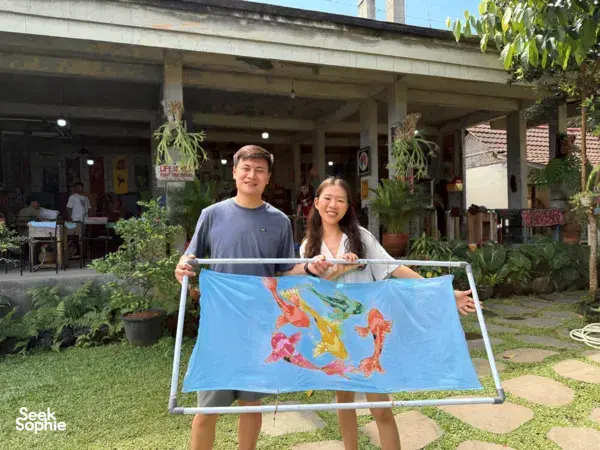 Visitors at Five Arts Studio in Keliki village holding a finished batik cloth outside the artisan courtyard in Bali, Ubud
