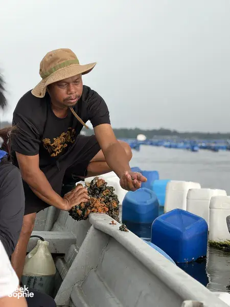 Young Nautilus host sorting marine catch into a tray on a boat off Johor Bahru during the Orang Seletar heritage tour