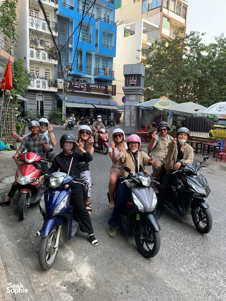 Motorbike group posing for a guide on a busy street in Ho Chi Minh City during the Saigon hidden craft alleys tour