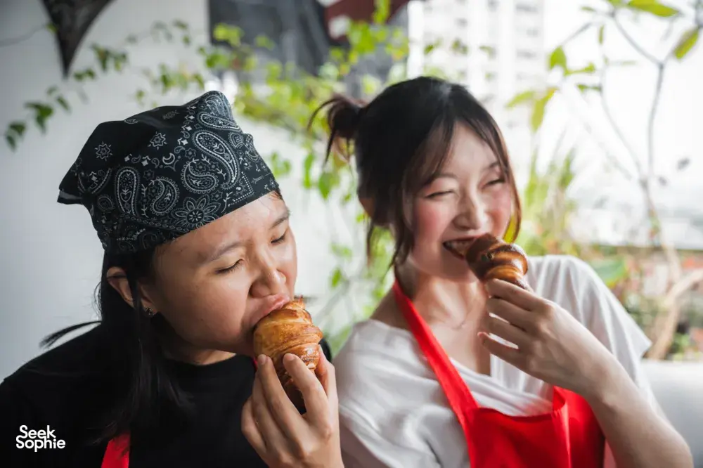 Two guests tasting flaky croissants at a French Cooking Lab bake-in-home session in Singapore courtyard dining