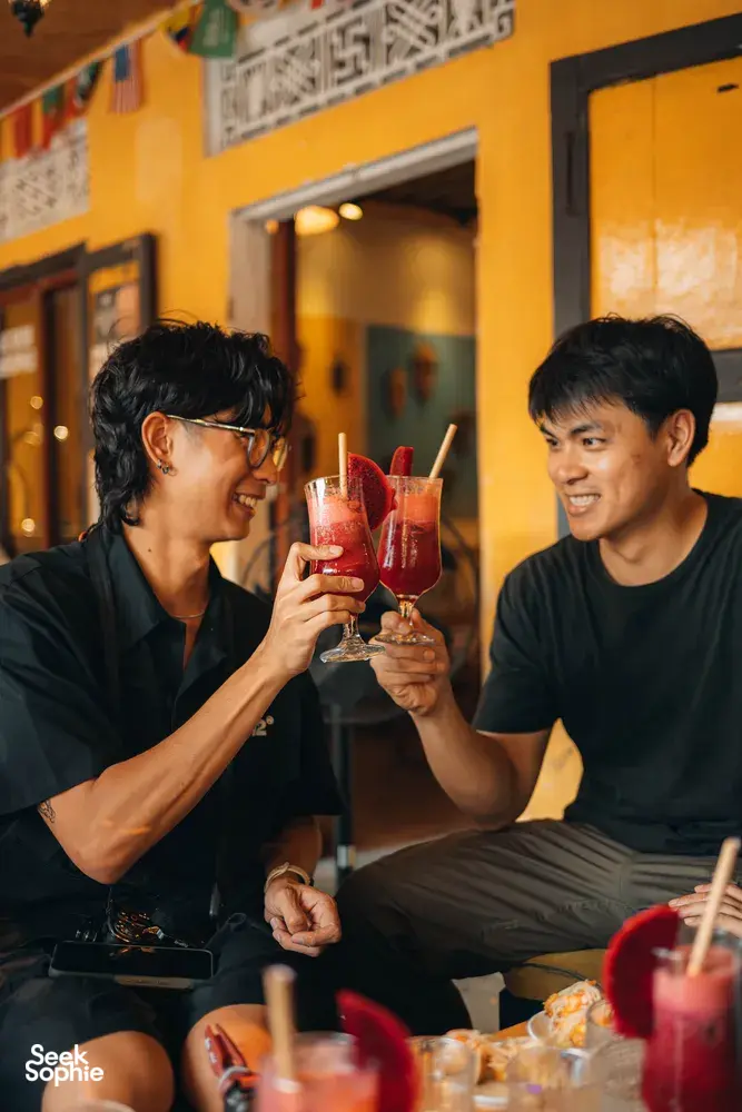 旅人在庭院中举起红色鸡尾酒碰杯，参加 Secret Experiences 的会安鸡尾酒之旅