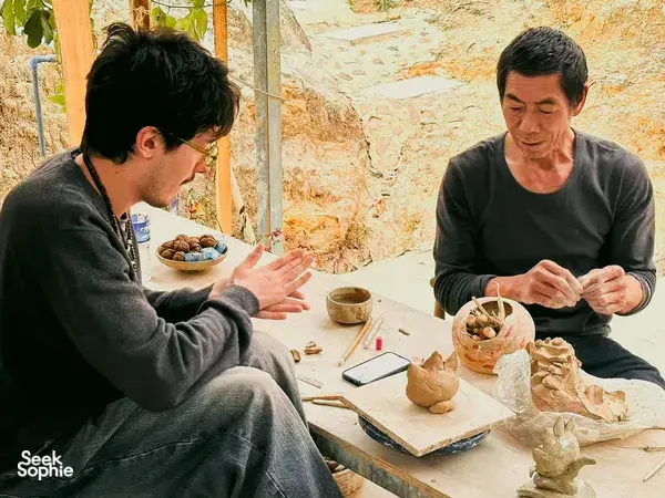 Friends sit at a pottery workspace shaping and trimming clay figures during a visit to an ancient pottery village in Dali