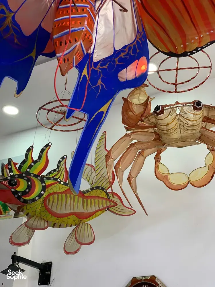 Fish- and animal-shaped paper lanterns hanging from the ceiling in a Ho Chi Minh City craft workshop for lantern-making