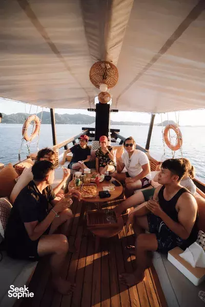 Group enjoys breakfast on the deck of a phinisi boat with open-ocean views during a Komodo stay in Labuan Bajo