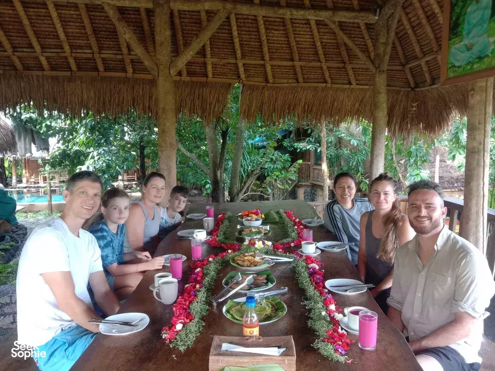 People gathered around a decorated dinner table with plates, drinks and candlelight at Omunity Bali’s open-air meal setting, Bali