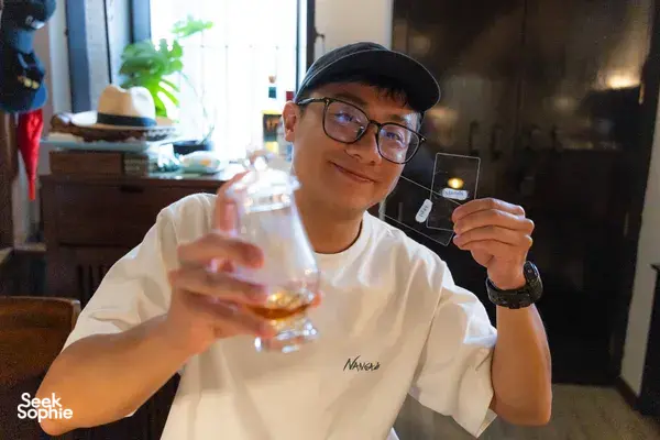 Scotch & Sambal host-led whisky tasting in Singapore: a man smiles while holding a dram glass at the hidden home bar