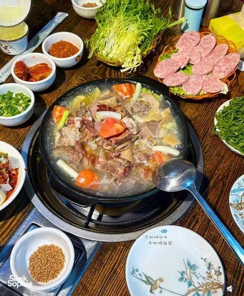 Lijiang food hunt with local stories: sizzling hotpot of sliced meats with vegetables and spice bowls on a wooden table