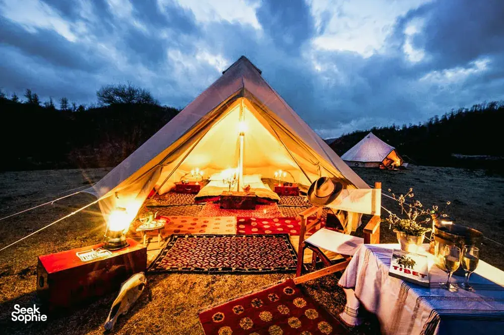 Candlelit tent camp in Shangri-La’s remote valleys, with a dining area laid out inside a large nomadic caravan tent