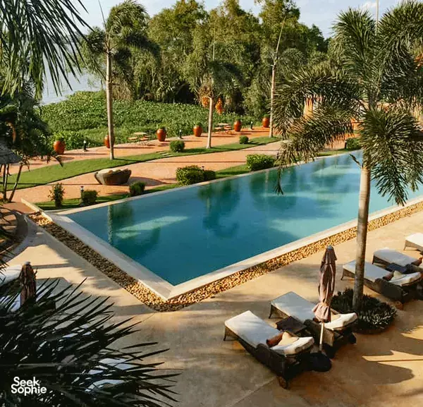 Swimming pool at The Island Lodge, a luxurious Mekong Delta resort, framed by tropical gardens and sun loungers
