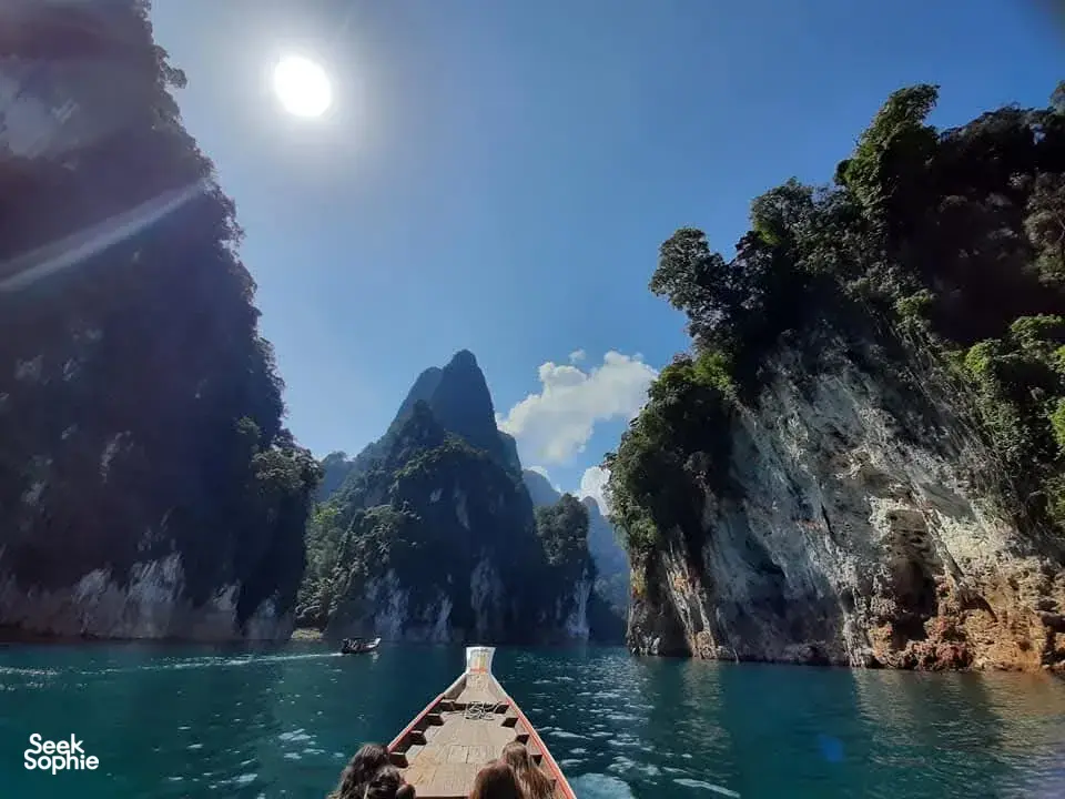 Boat deck with a drink bottle under bright sun, cruising through narrow karst bays in Khao Sok, Cheow Lan Lake