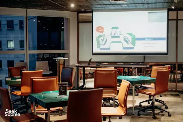 Singapore training room set up with mahjong tables and a projector screen, ready for a group briefing before play