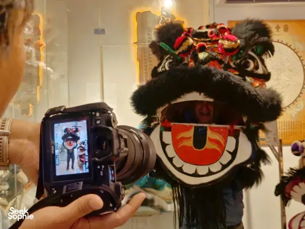 Close-up filming moment in a Ho Chi Minh City kung fu and lion dance workshop, with a lion head puppet filling the frame