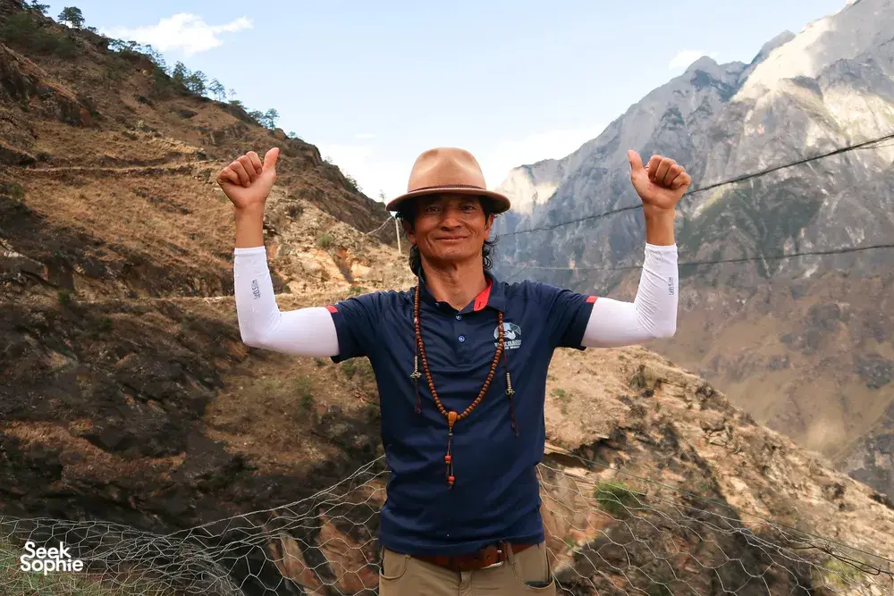 Trekker on the Lesser-Known high trail of Tiger Leaping Gorge in Lijiang, raising both arms beside a safety net