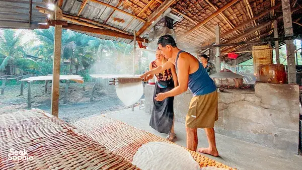 Traveller showering or rinsing under an open bamboo roof in the Mekong Delta, surrounded by outdoor wash basins