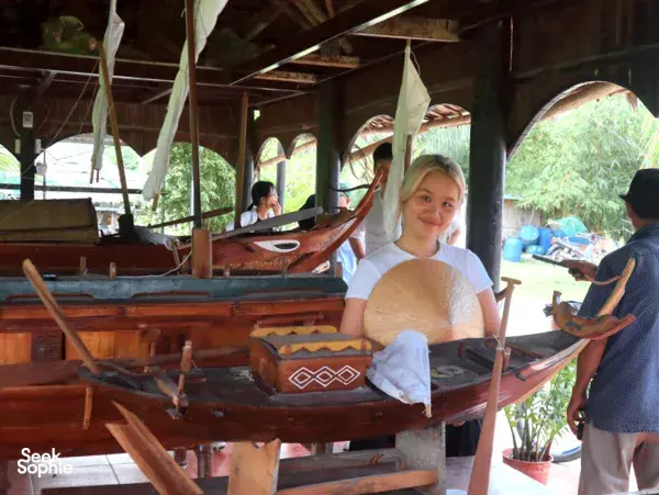 Traveller seated on a wooden river boat during a calm ride, with another boat and oars visible near Hoi An