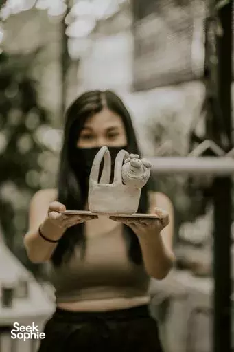 Participant holding a white ceramic sculpture at Tiong Bahru Pottery’s outdoor backyard studio in Singapore, after glazing