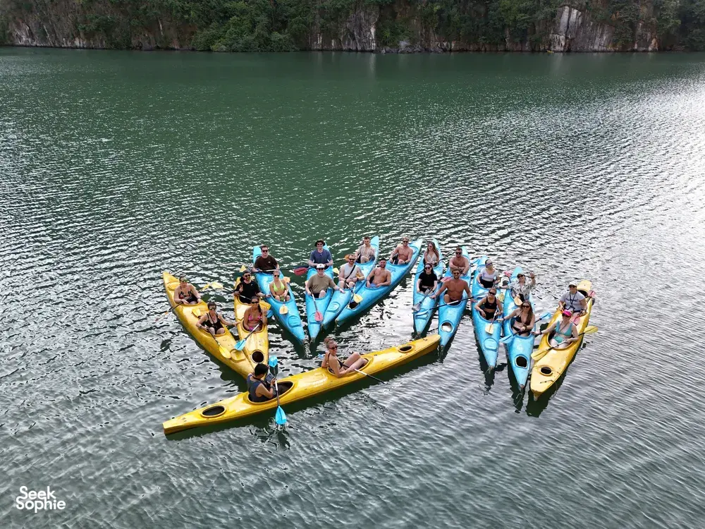 Kayakers in bright yellow boats on Halong Bay, gathered in formation with life jackets for a fun water activity