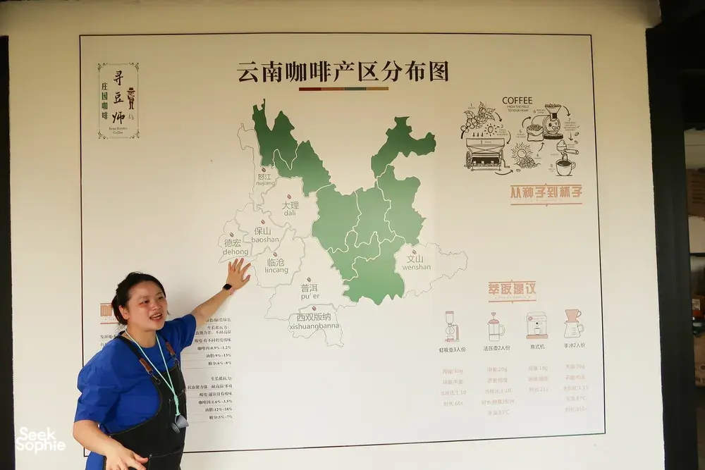 Seeker Yunnan Coffee Estate host in Lijiang pointing to a wall poster map of Yunnan’s coffee regions today
