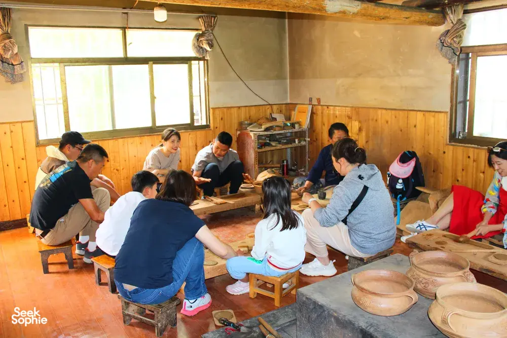 Travellers shaping clay in a wooden Tibetan pottery studio in Shangri-La, part of the Meet a Lama home lunch experience