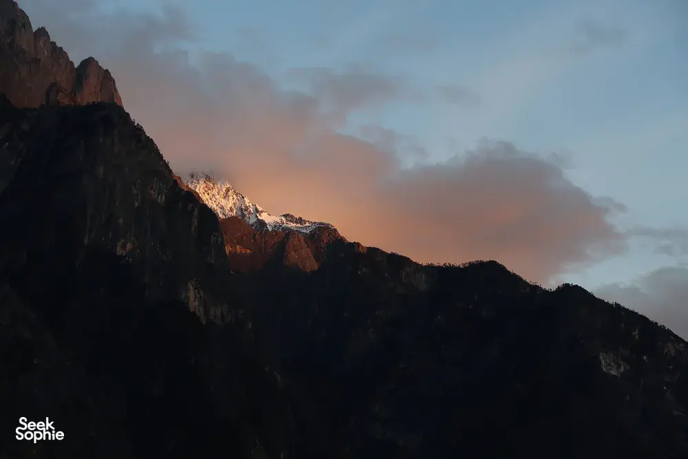 Twilight mountain ridges over Tiger Leaping Gorge near Lijiang, with clouded sky glowing beyond the trail during the 2D1N high hike