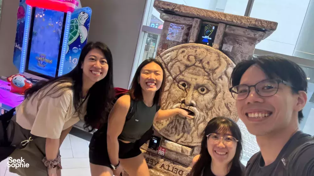 Team members smiling beside an arcade game display during a clue-chasing team challenge at Marina Central, uncover Singapore hidden gems