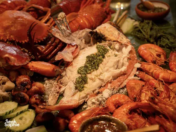 Close-up of Asian seafood platter with wild greens from Primateve private dining Singapore, scattered with herbs and vegetables