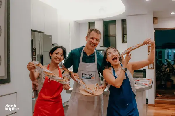 Singapore cosy loft French baguette workshop at French Cooking Lab: smiling guests holding flour-dusted baguettes, workshops in Singapore