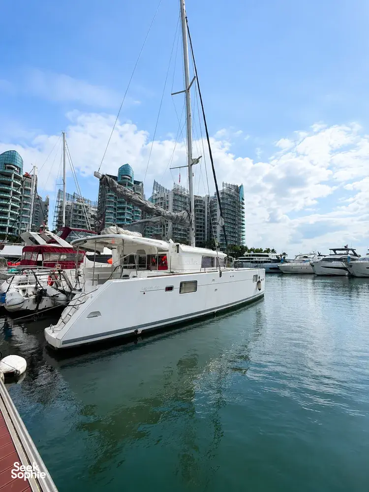 Zen Sea catamaran moored in Singapore marina with sail rig and skyline towers, ready for a kayak, SUP and snorkel cruise