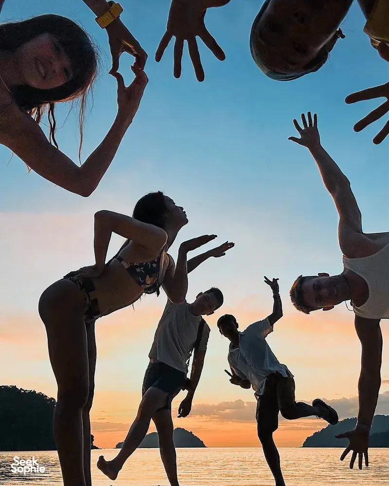 Friends jumping on the beach at sunset during a 2D1N Surin Island beach camping trip with Moken guides near Khao Lak