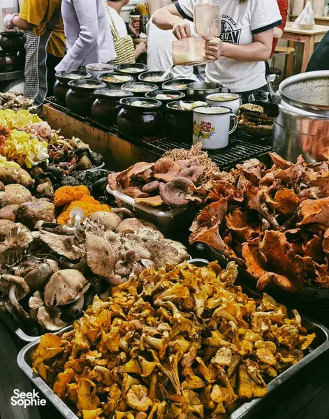 Lijiang street food stall with trays of grilled and spiced dishes and paper cups, as part of a local stories food hunt