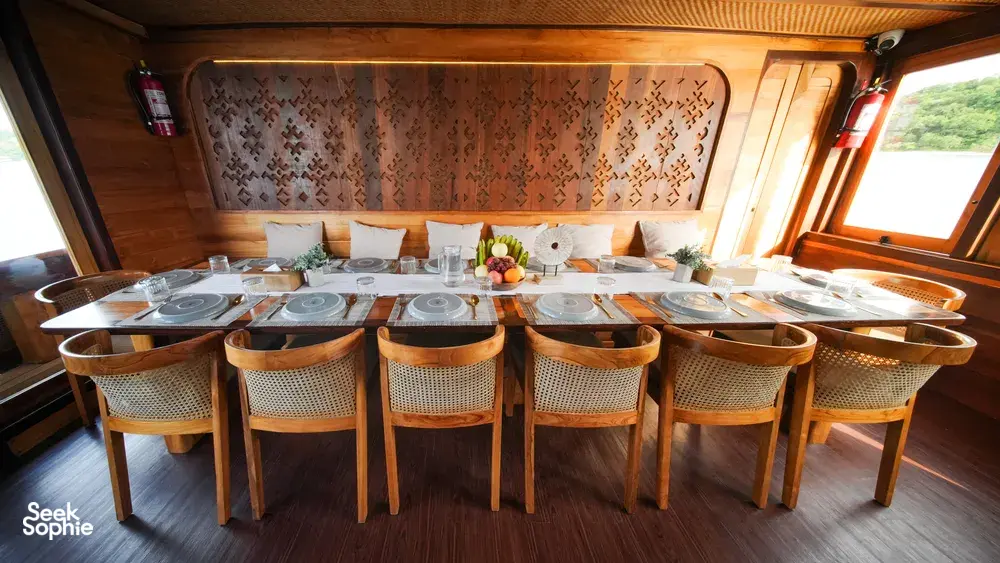Banquet-style dining set with woven-back chairs on a phinisi cruise, ready for shared meals in Labuan Bajo