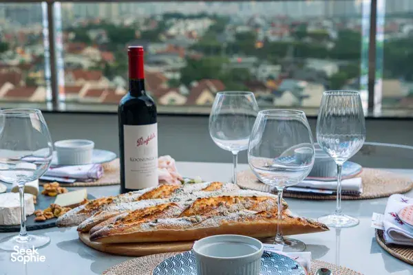 Close-up of French baguettes, a red wine bottle and glassware on a Singapore loft dinner table—private dining Singapore